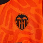 Close-up of orange Valencia CF jersey fabric with partial crest and text Valencia C.F.