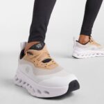 Beige and white chunky sneakers with a thick white sole, worn with black leggings.