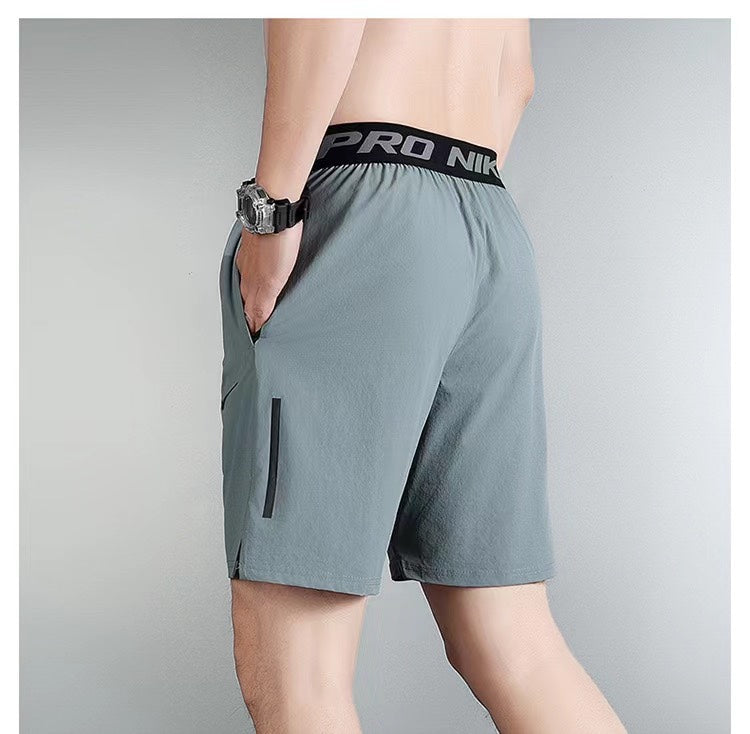 cfa08d41 | UAE SPORT STORE Rear view of a man wearing gray athletic shorts with a black waistband and a vertical zip pocket on the side; his hand in the pocket.