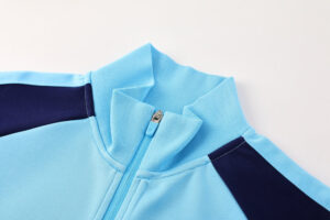cff48a13 | UAE SPORT STORE Light blue zip-up jacket with dark navy side panels, shown from the collar area (close-up).