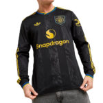 Black Manchester United long-sleeve football jersey with Snapdragon sponsor and yellow accents worn by a person