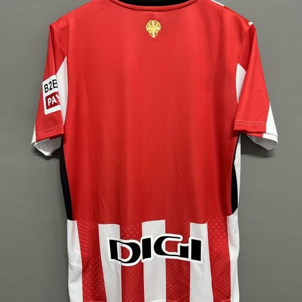 Red sports jersey on hanger with white vertical stripes at the hem and sponsor logo 'DIGI' at the bottom back edge.