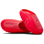 Bright pink slip-on slide sandals with a chunky ridged sole and perforated upper, featuring a Nike swoosh on the strap.