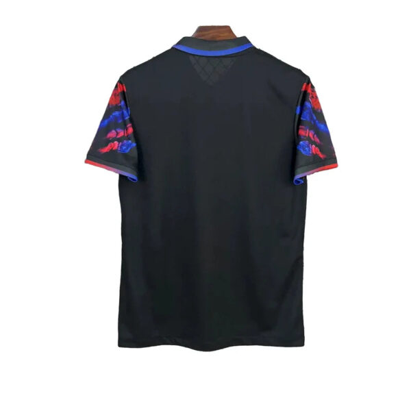 Back view of a black sports jersey with short sleeves featuring red and blue tie-dye patterns and blue trim at the collar.