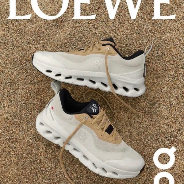 Loewe advertisement showing beige and white sneakers on a gravel surface with a large LOEWE logo above them.