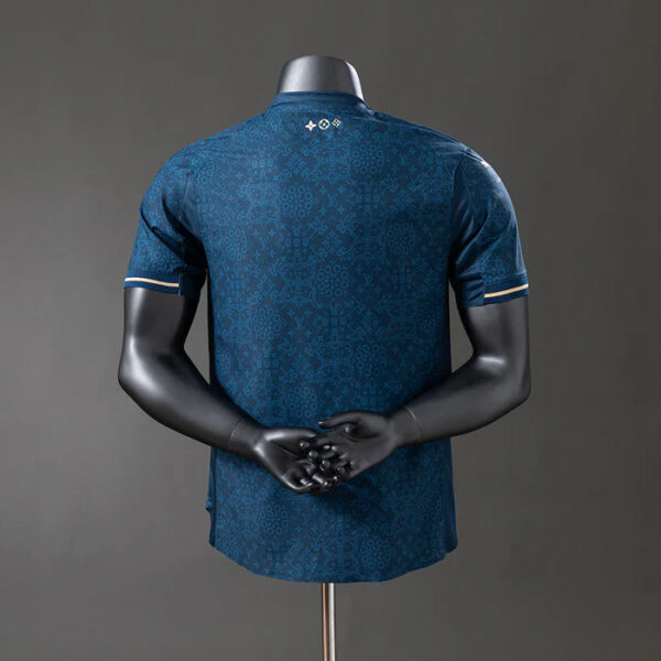 Back view of a blue patterned athletic jersey on a mannequin, short sleeves with gold trim on the cuffs.