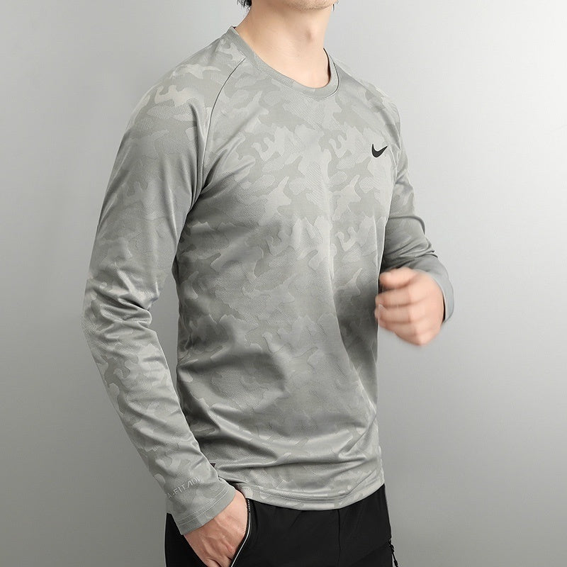 d2214a76 | UAE SPORT STORE Male model wearing a light gray camouflage-patterned long-sleeve athletic shirt with a small black Nike swoosh on the chest.