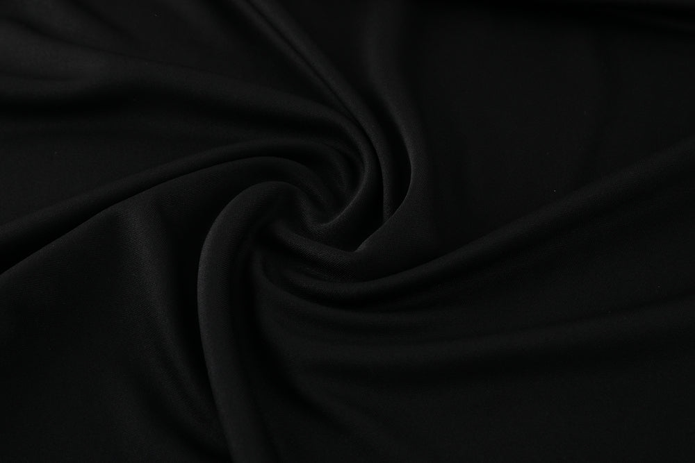 d2b00fba | UAE SPORT STORE Close-up of smooth black fabric with soft folds forming a spiral pattern.