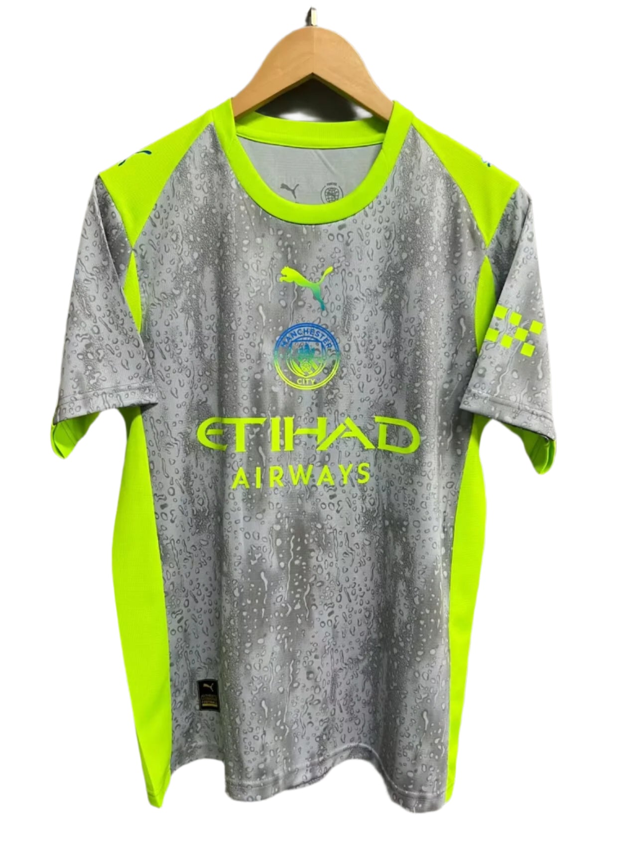 d2cf52ce Manchester City away jersey on a wooden hanger, neon yellow and grey with a rain-drop pattern and sponsor logos (Etihad).