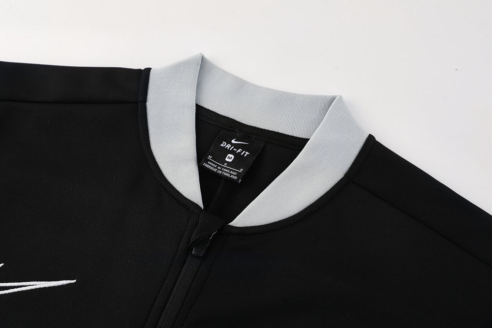 d3174007 | UAE SPORT STORE Close-up of a black zip-front athletic jacket with a light gray ribbed collar; tag shows Nike Dri-FIT.