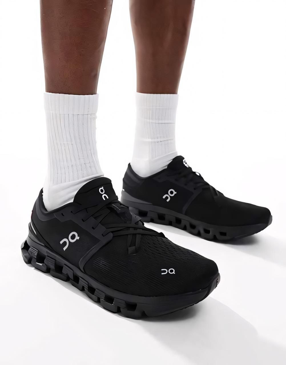 d46424d2-46c8-44da-8ad4-d3f119112989 | UAE SPORT STORE Black On running shoes worn with white socks, shown from the ankle down against a white background.