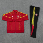 Arsenal red track jacket with yellow piping and crest, shown with black pants featuring yellow stripes and Arsenal badge.