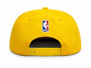 Yellow NBA baseball cap seen from the back with a plastic adjustable strap and a small logo patch on the crown.