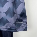 Close-up of dark blue camouflage fabric with visible AEROREADY branding on the edge of a garment pocket or seam