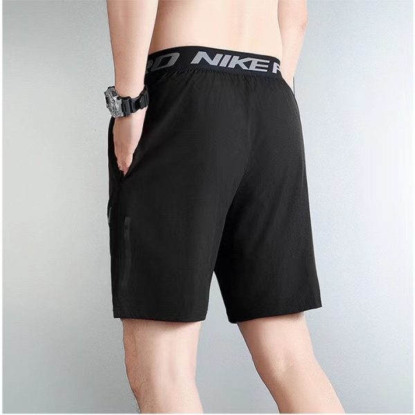 Back view of a person wearing black Nike athletic shorts with an elastic waistband and hand in pocket, gym/athletic style.