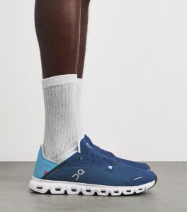 d4d0c179-adf8-4eea-ade3-91861190c0cb | UAE SPORT STORE Blue running shoes with a white segmented sole, worn with white crew socks, side view.