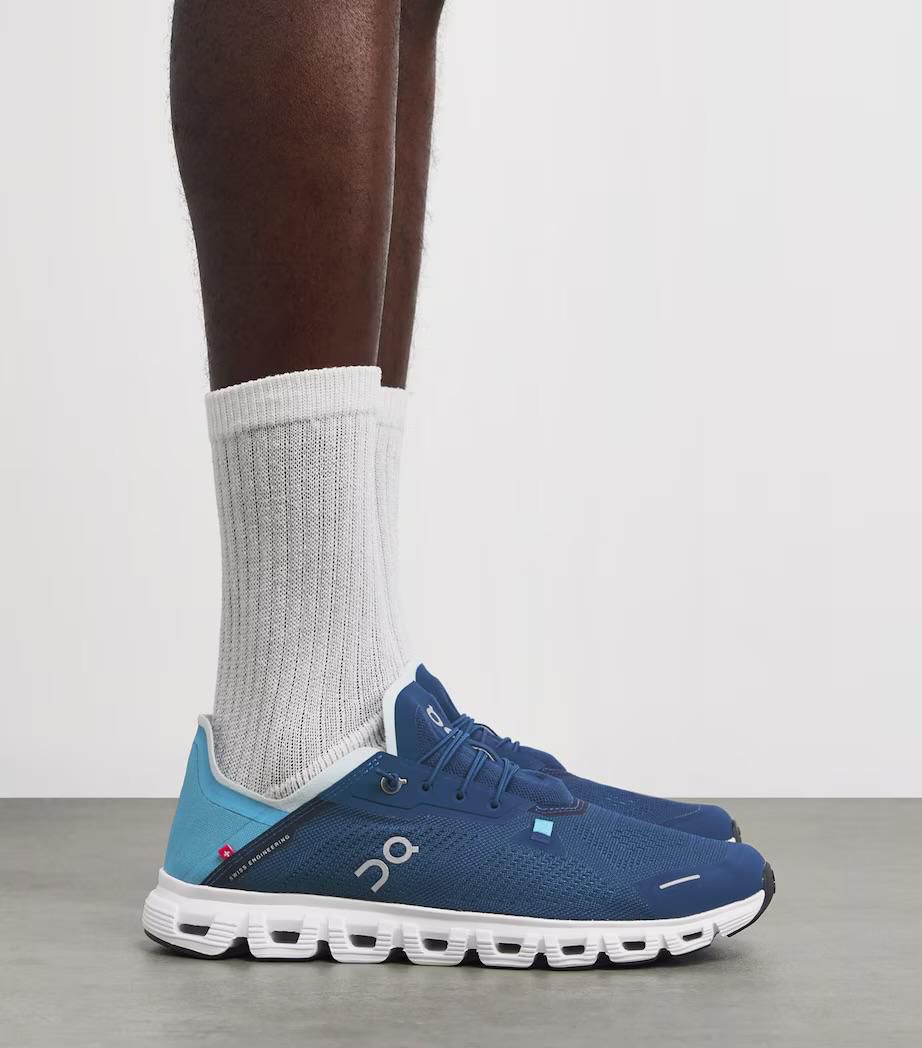 d4d0c179-adf8-4eea-ade3-91861190c0cb | UAE SPORT STORE Blue running shoes with a white segmented sole, worn with white crew socks, side view.