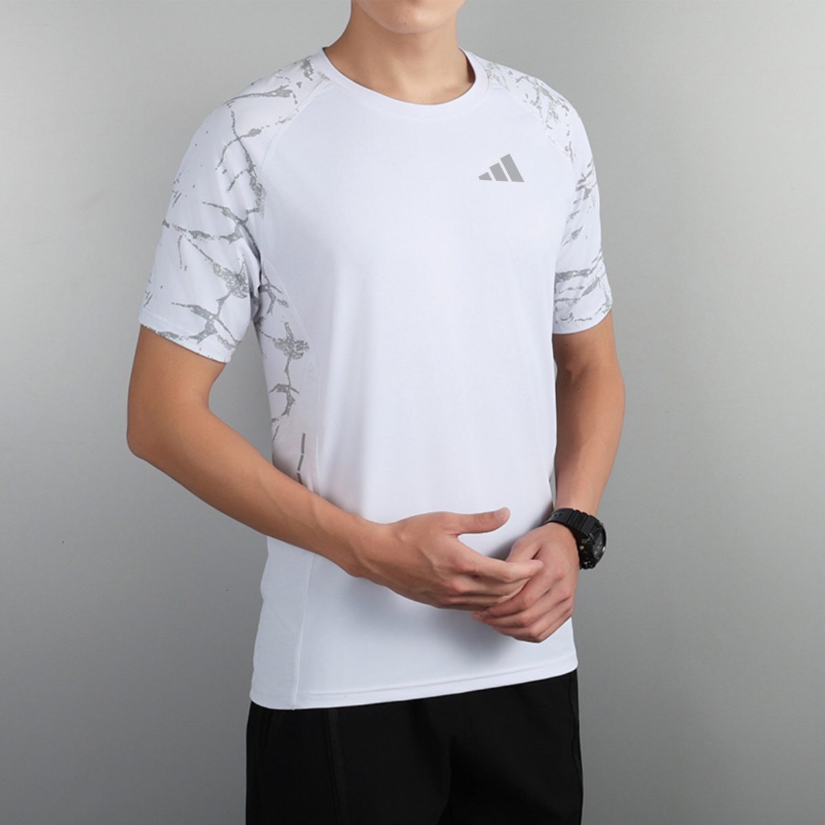 Person wearing a white athletic T-shirt with gray marble sleeves and a small Adidas logo on the chest.