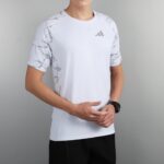 d5658f68 | UAE SPORT STORE Person wearing a white athletic T-shirt with gray marble sleeves and a small Adidas logo on the chest.
