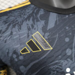 Close-up of a dark camo-pattern sports jersey with a yellow-outlined three-bar Adidas-style logo on the chest area.