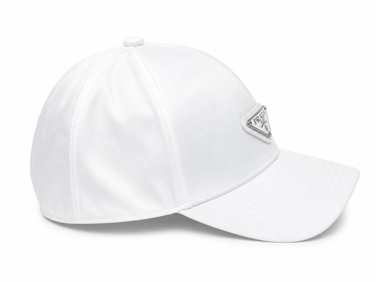 White baseball cap with a triangular Prada logo badge on the front and a curved brim.