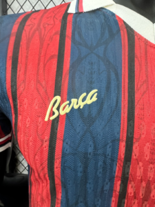 d7456706_15943edb-c927-4977-8150-1f40bd3897ec | UAE SPORT STORE Close-up of a red and blue striped jersey with a yellow cursive 'Barça' logo.