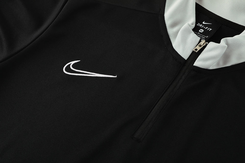 d77edcfc | UAE SPORT STORE Close-up of a black Nike Dri-FIT jacket with a white swoosh logo and a zipper at the collar area.