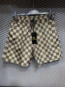 Patterned Louis Vuitton swim shorts on a hanger with a black LV tag visible.