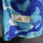Close-up of a gold-embossed badge on blue camo fabric reading 'AUTHENTIC LICENSED PRODUCT' (brand license tag).