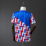 Back view of a blue jersey with red and white geometric stripe pattern on a mannequin.