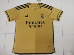 Yellow Real Madrid football jersey with black Adidas stripes on shoulders and Emirates sponsor text reading 'Emirates Fly Better' front and center.