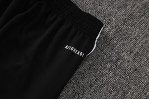 Close-up of black athletic shorts with an elastic waistband and the 'AEROREADY' logo on a gray carpet.