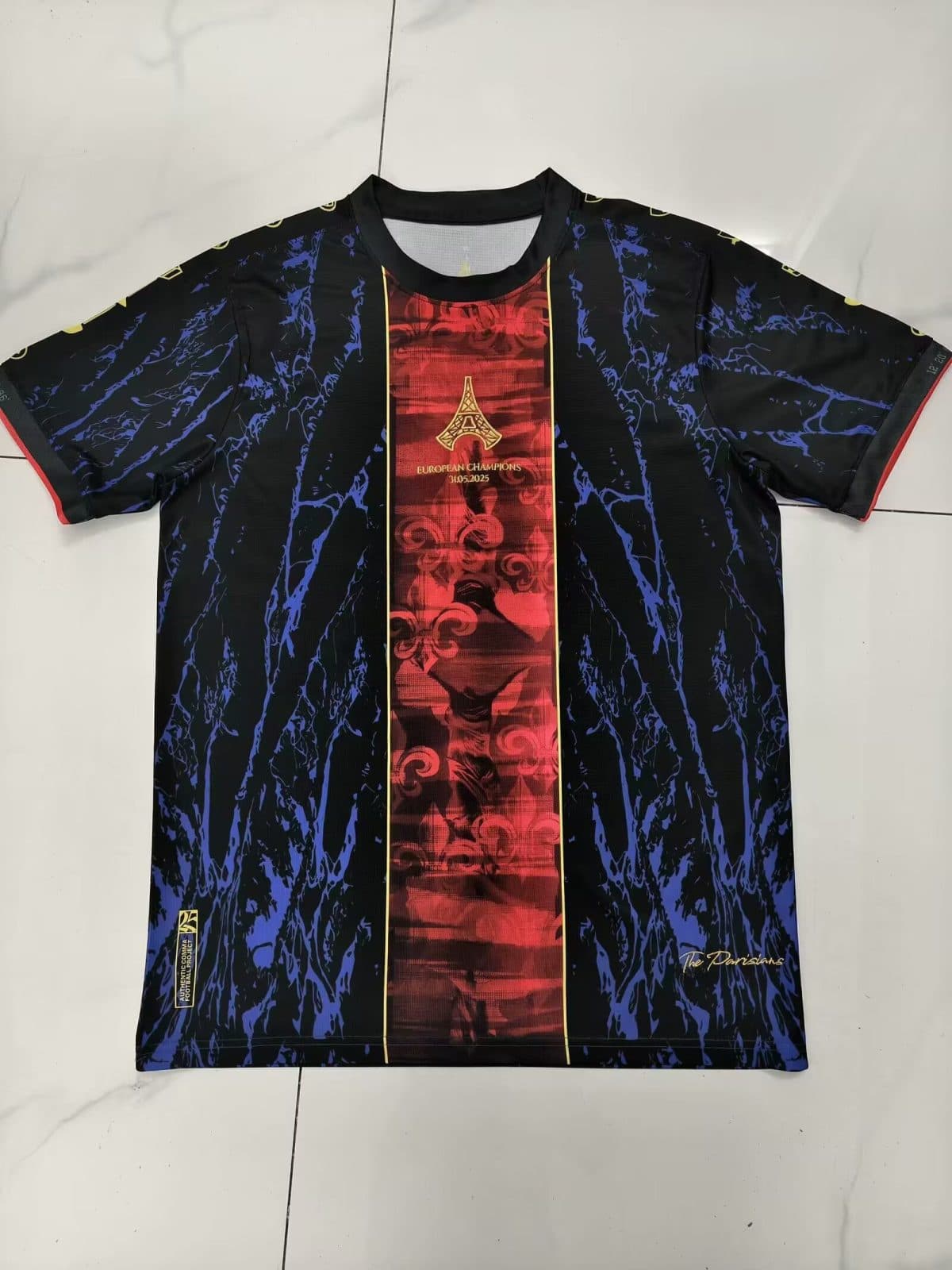 Black soccer jersey with blue marble-like pattern and a red central panel featuring an Eiffel Tower crest and 'European Champions' date text, laid flat on a light surface.