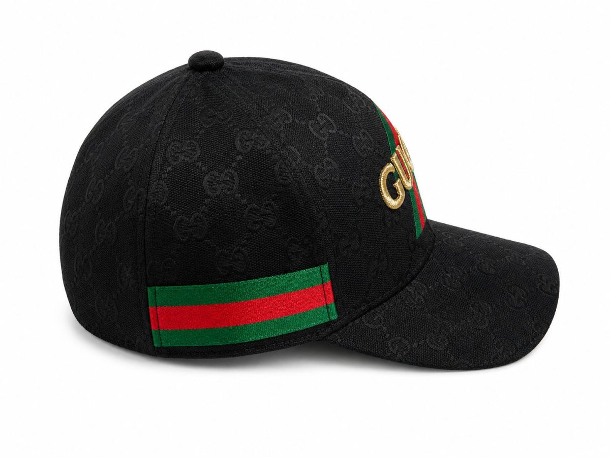 Black Gucci baseball cap with embossed interlocking G pattern and gold GG logo; green and red striped detail on the side.