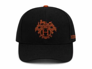 Black baseball cap with orange ornamental crest embroidery on the front and an orange button on top.