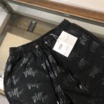 Black Dior-logo track pants with an all-over print, elastic waistband and drawstrings, tag attached on display in a glass case.