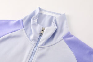 dc108e24 | UAE SPORT STORE Close-up of a pastel blue and lavender zip-up jacket collar with visible metal zipper.