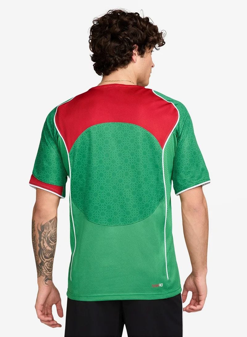 dc5cd99f-e36a-44cd-87e7-125490e3a81e | UAE SPORT STORE Back view of a green and red sports jersey with a circular darker green pattern on the back and white piping.