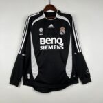 dc7390d7_9d04a679-c92b-4d49-8fc9-5cc89dc0ffe6 | UAE SPORT STORE Real Madrid black soccer jersey with white piping and crest, Adidas logo, Siemens sponsor, hanging on a wooden hanger.