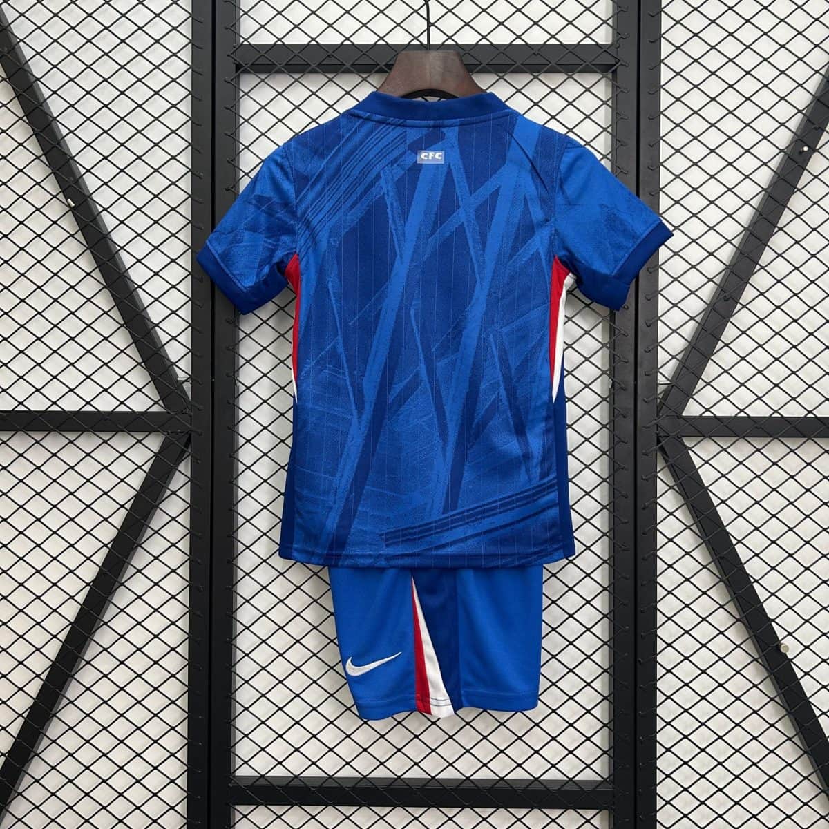Blue sports jersey on a hanger seen from the back, with a small 'CFC' label and a Nike swoosh visible on the shorts below.
