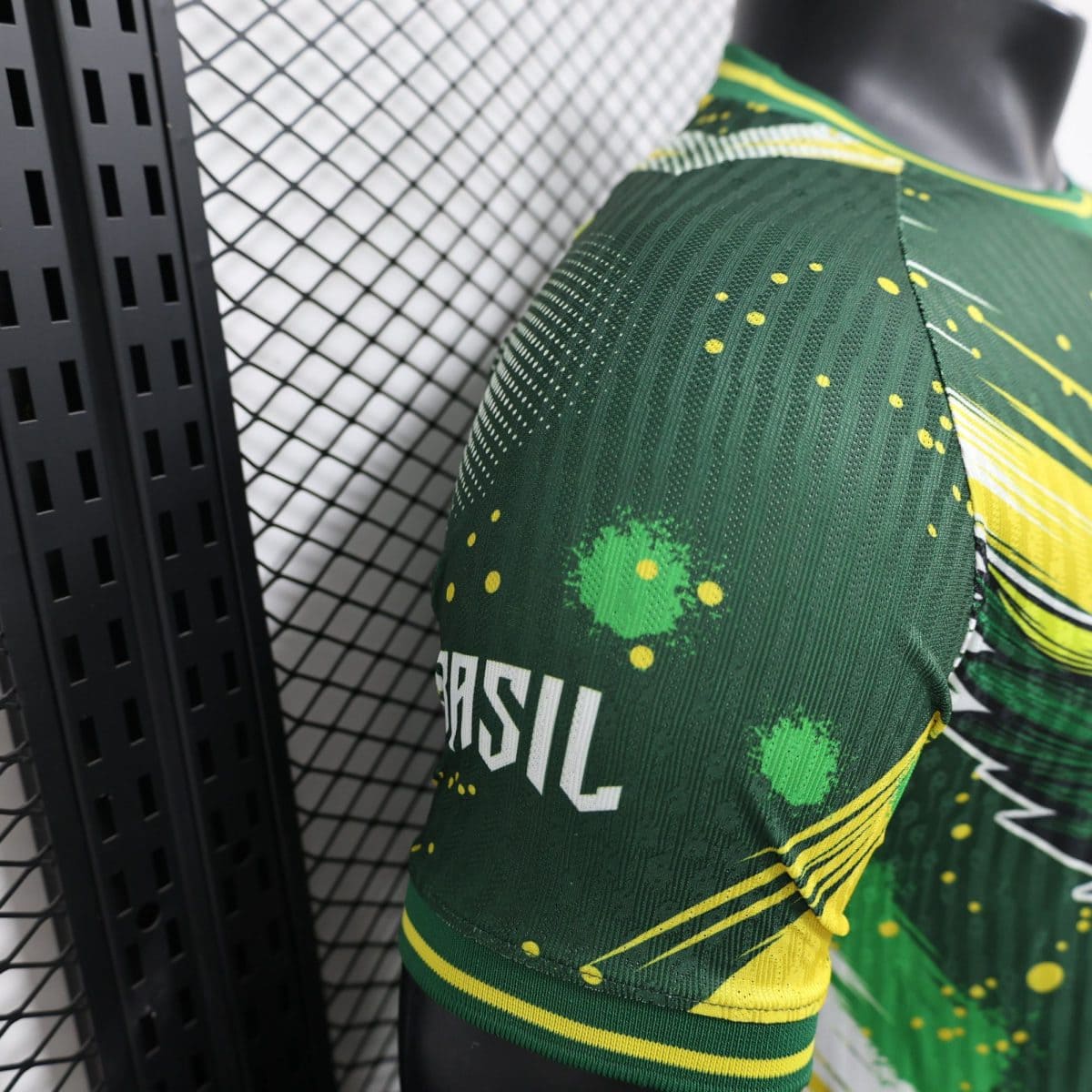 Close-up of green athletic fabric with yellow dot pattern and diagonal stripes, near a black perforated display rack.