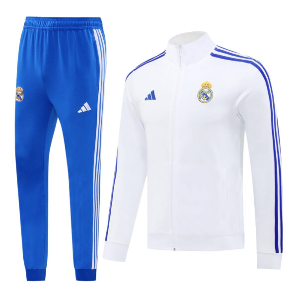 White Real Madrid track jacket with blue stripes and crest, paired with blue Adidas track pants featuring white stripes and club badge