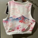 White sleeveless crop top with pink cherry blossom and mountain print, resembling a Japanese-inspired design.