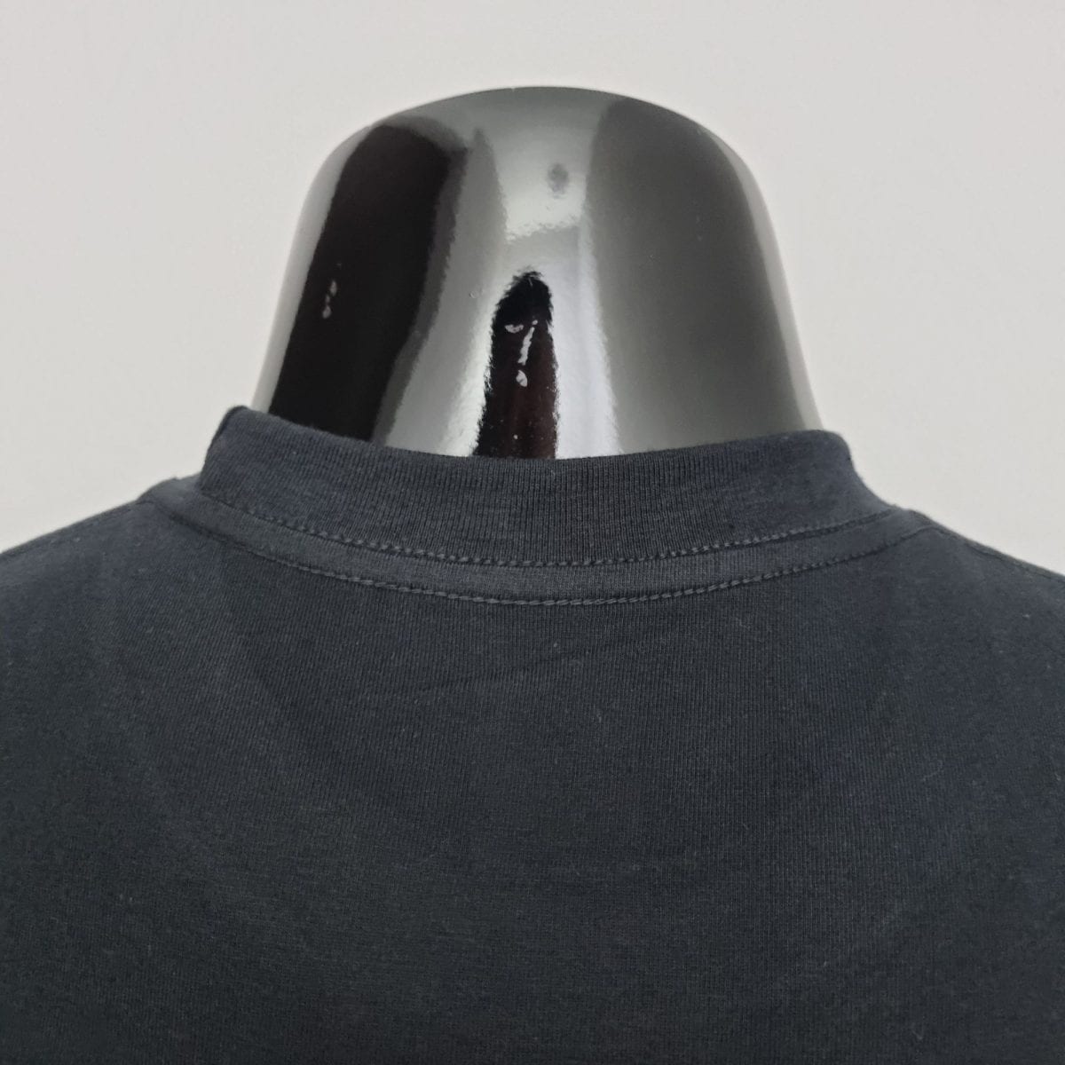 Close-up of a shiny curved metal surface resting above a gray sweatshirt neckline.