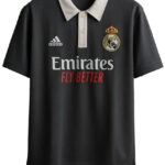 Black Real Madrid polo shirt on a hanger with a white collar, featuring the Emirates Fly Better sponsor and the club crest on the chest.