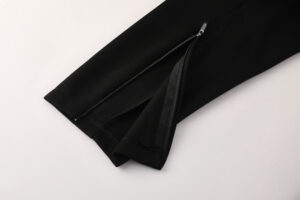Black pants leg featuring a metal zipper along the ankle, partially unzipped.