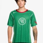 Male model wearing a green soccer jersey with white piping and the number 90 on the chest.