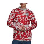 Man wearing a red and white camouflage Manchester United long-sleeve jersey with Adidas logo and club crest on chest.