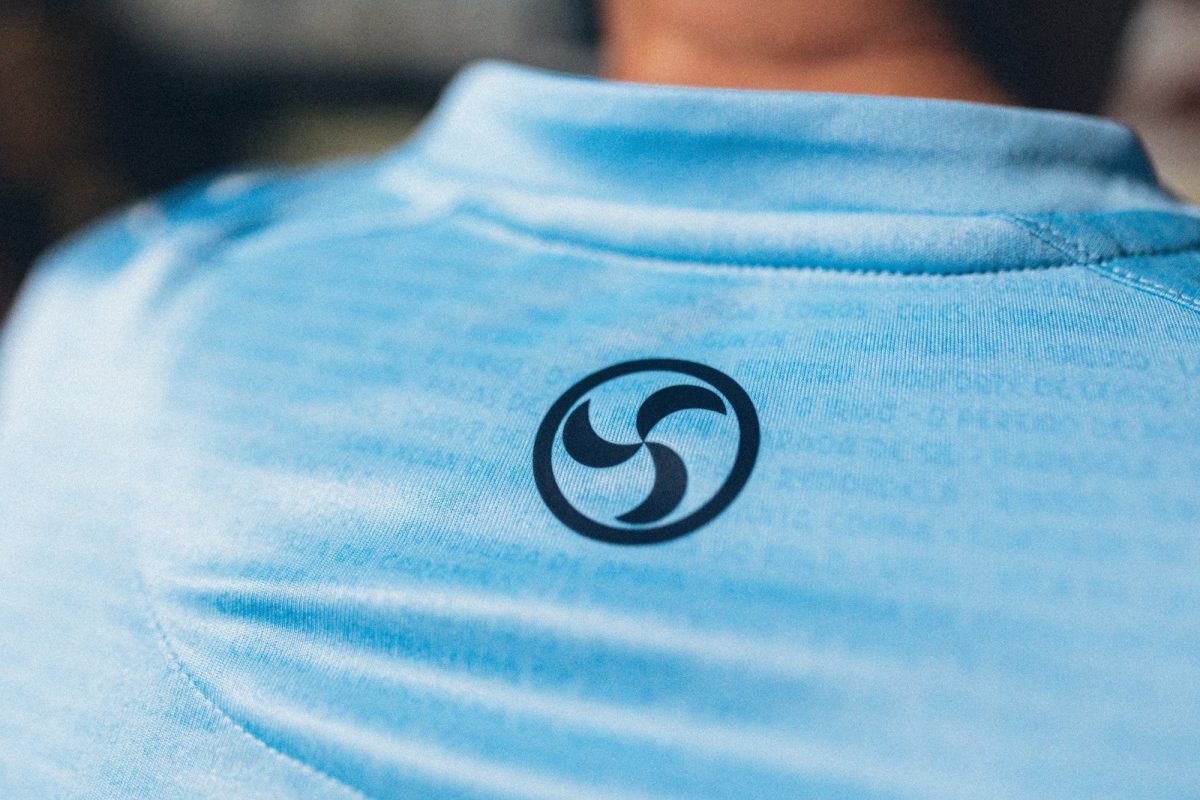Close-up of light blue fabric with a black circular logo of three curved shapes.