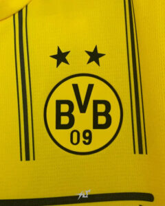 Close-up of a yellow Borussia Dortmund jersey with the BVB 09 crest and two black stars above it.